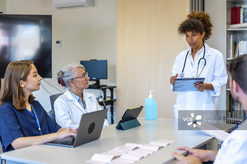 医生和护士在现代医院环境中参加医疗简报，分析患者数据和治疗方案图片素材