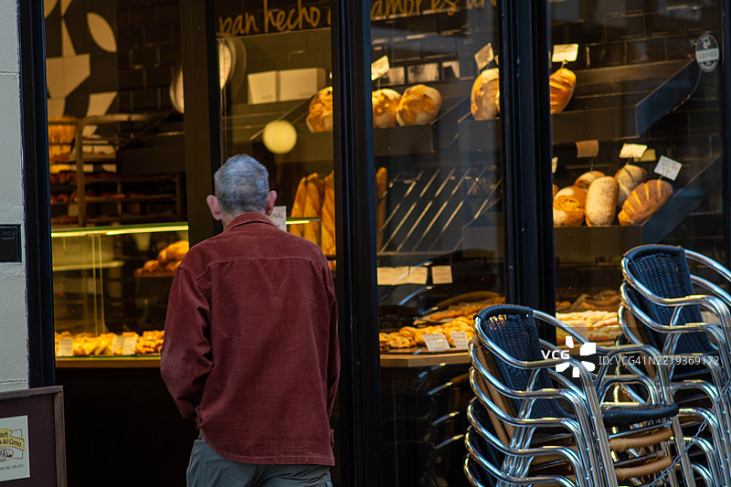 成熟男士在面包店橱窗前欣赏新鲜面包图片素材