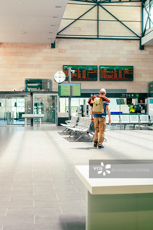 游客在火车站查看显示屏上的列车时刻表图片素材