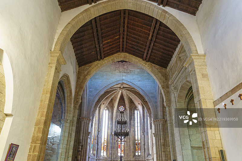 西班牙加利西亚贝坦索斯的一座教堂内部，拥有拱形天花板、彩色玻璃窗、木质天花板和石拱门。图片素材
