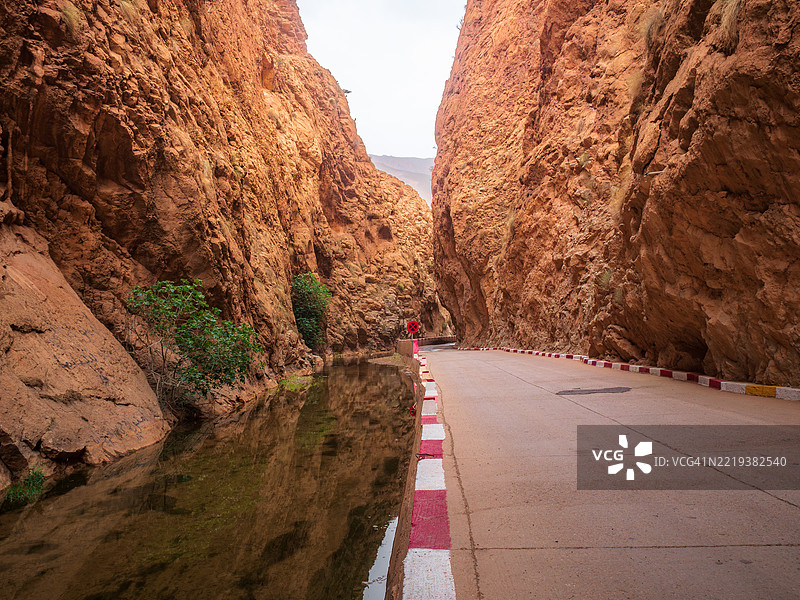 著名的达德斯河峡谷中一条空旷道路的广角视图，通向峡谷中的狭窄通道，岩壁在水中倒映，布马尔内·达德斯 - 提尼尔省 - 德拉-塔菲拉勒 - 摩洛哥。图片素材