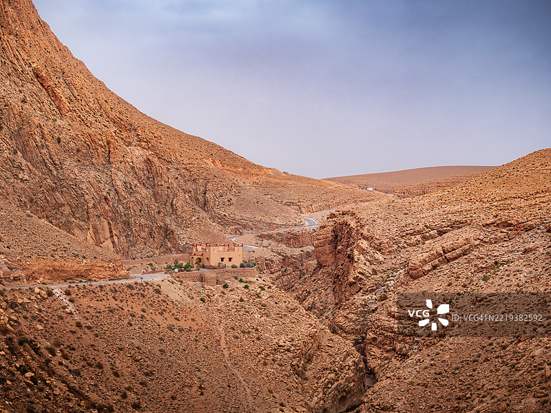 沿着著名的达德斯峡谷蜿蜒而上的空旷山路，峡谷由沉积岩构成，悬崖边缘有一座传统房屋，布马尔内·达德斯（Boumalne-Dadès） - 丁吉尔省 - 德拉-塔菲拉勒 - 摩洛哥。图片素材