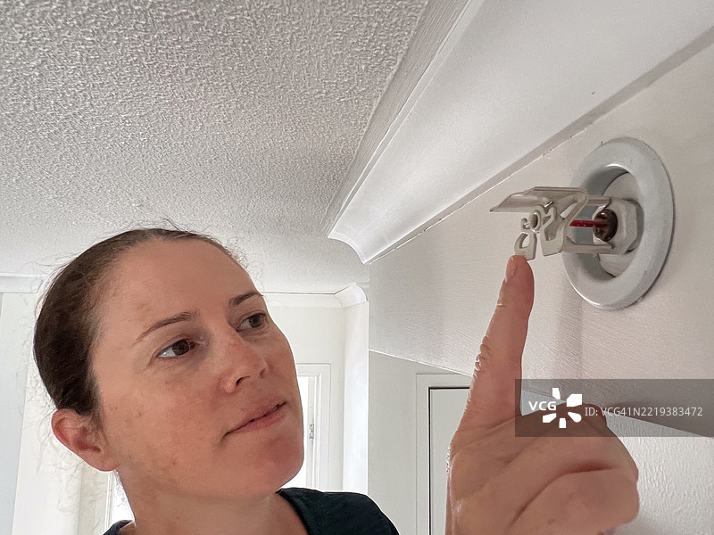 女性检查消防喷头的检验情况图片素材