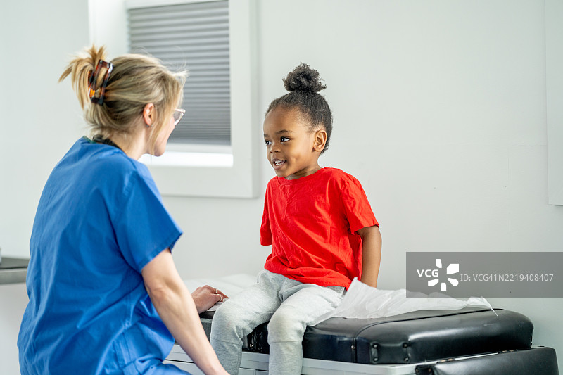 微笑的孩子在医生的检查台上与护士进行医疗检查图片素材