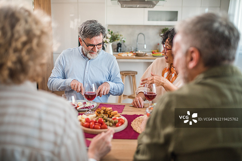 一小群人一起享用午餐，品尝美味的食物和优质的葡萄酒图片素材
