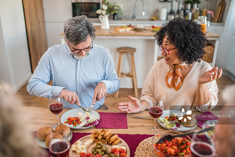 快乐的男女享受午餐，品尝开胃菜并喝着葡萄酒图片素材