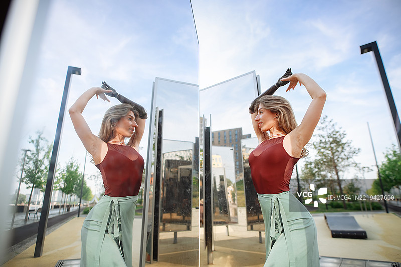 快乐的舞蹈：一位长发女性在城市的镜子旁，佩戴假肢图片素材