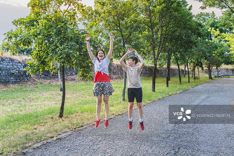 母亲与儿子之间的亲密时刻和无压力的生活方式。充满微笑和在公共公园跳跃的珍贵快乐家庭时光。图片素材