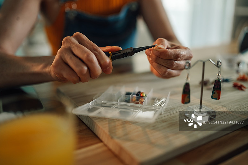 工匠使用钳子制作彩色珠子的手工耳环图片素材