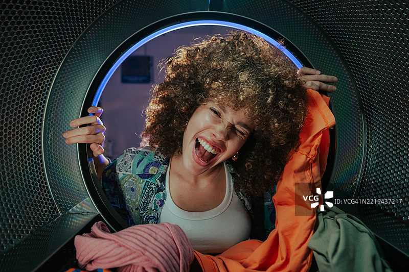 年轻女性在自助洗衣店享受洗衣乐趣图片素材