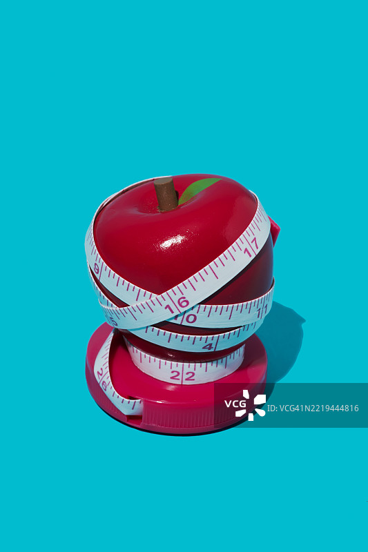 红色玩具苹果用卷尺包裹着图片素材
