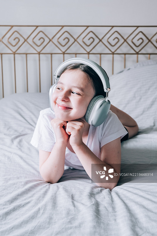 一个青春期前的女孩正在戴着耳机听音乐。图片素材