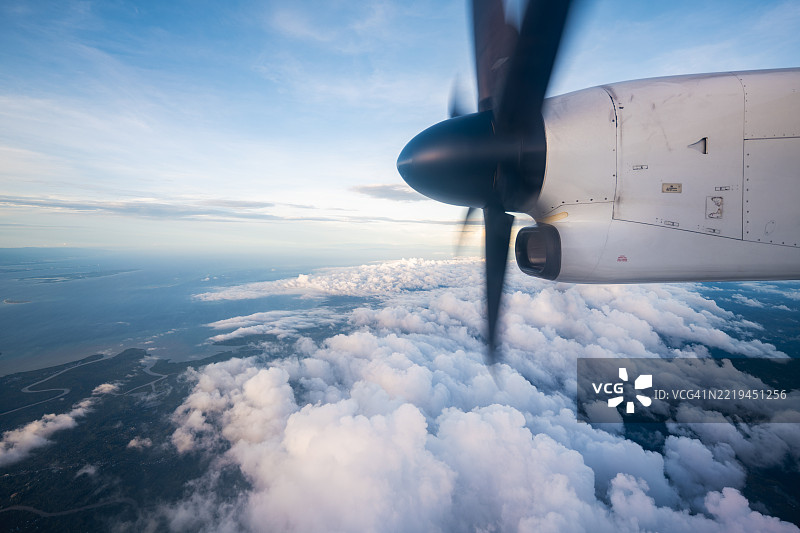 从螺旋桨飞机飞行中俯瞰海岸线和云朵的景象图片素材