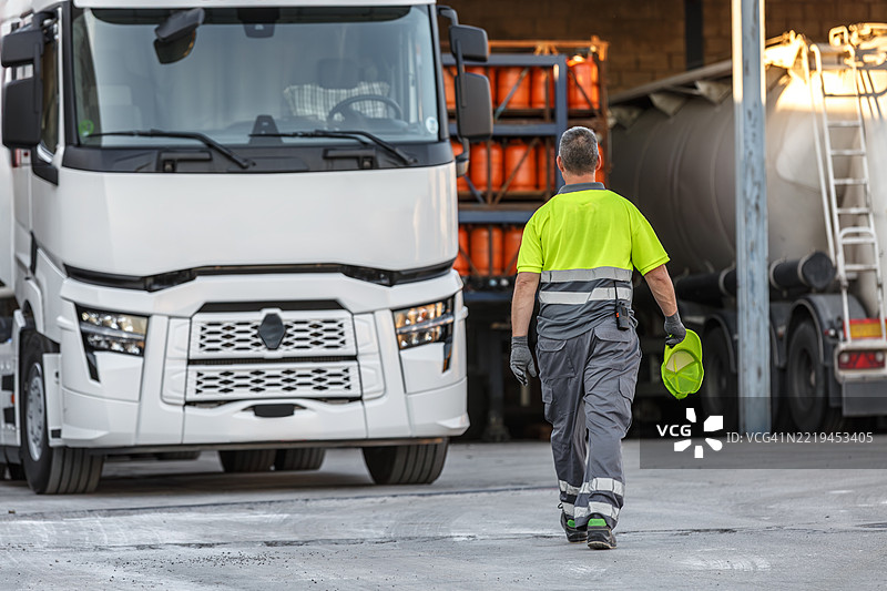 男子走向运输仓库的白色拖车卡车图片素材