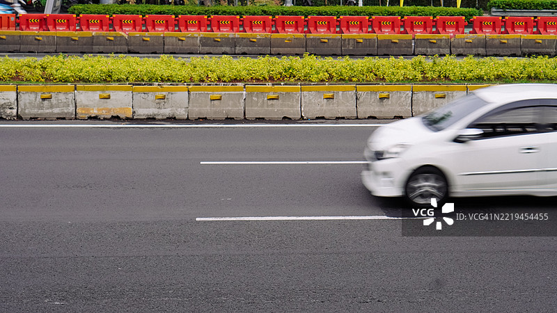 城市街道上行驶的白色汽车与路障图片素材