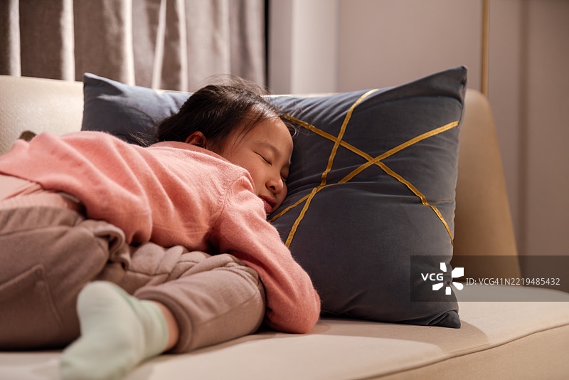 亚洲小女孩在酒店卧室的沙发上玩耍。图片素材