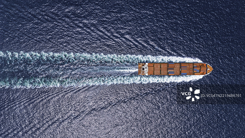 航拍视角下的集装箱船全速航行，伴随着美丽的波浪。图片素材