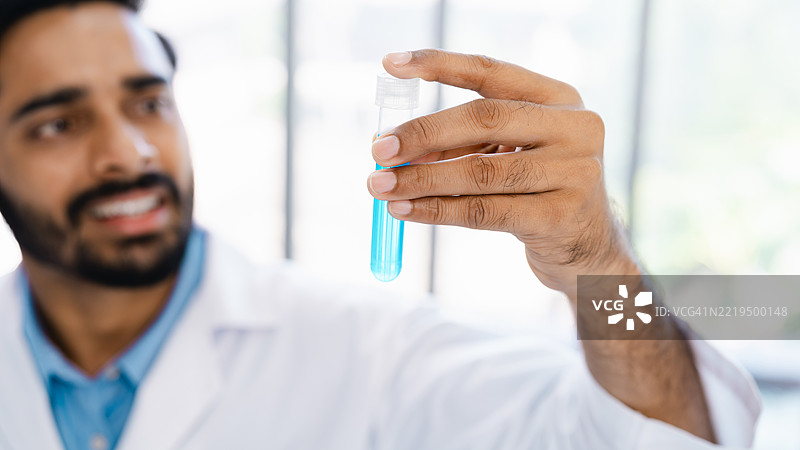 科学家在研究实验室中握着蓝色液体试管图片素材