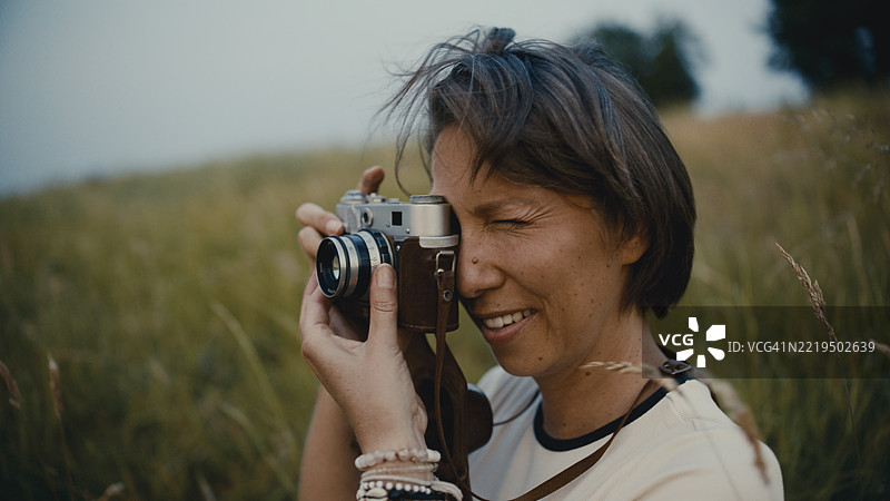 特写镜头：一位女性在高草丛中使用老式相机图片素材