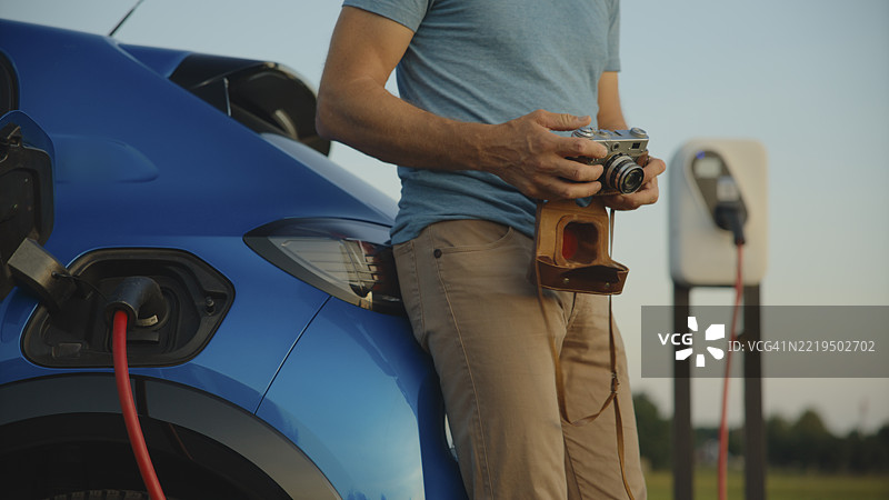 一名男子在等待电动车充电时，使用老式相机拍摄的特写镜头图片素材