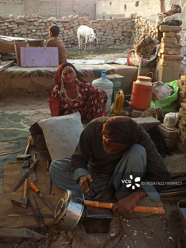 路边摊旁的铁匠与家人一起工作图片素材