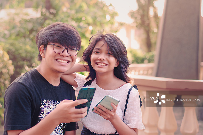 兄弟姐妹在公园里查看社交媒体图片素材