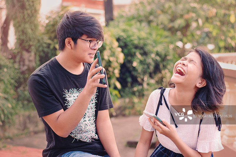 兄弟姐妹在公园里查看社交媒体图片素材