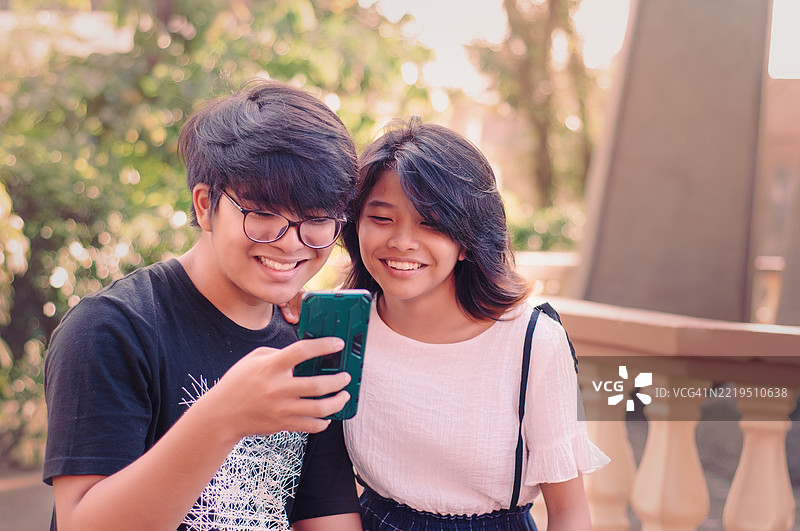 兄弟姐妹在公园里查看社交媒体图片素材