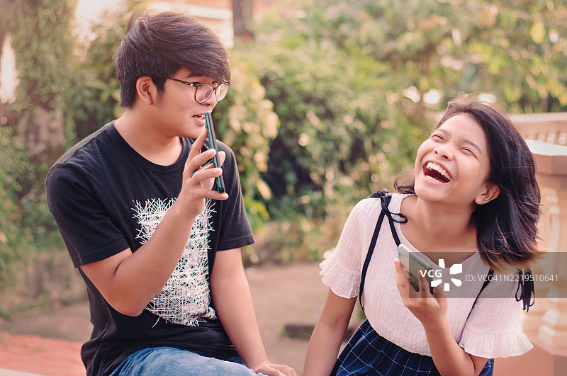 兄弟姐妹在公园里查看社交媒体图片素材