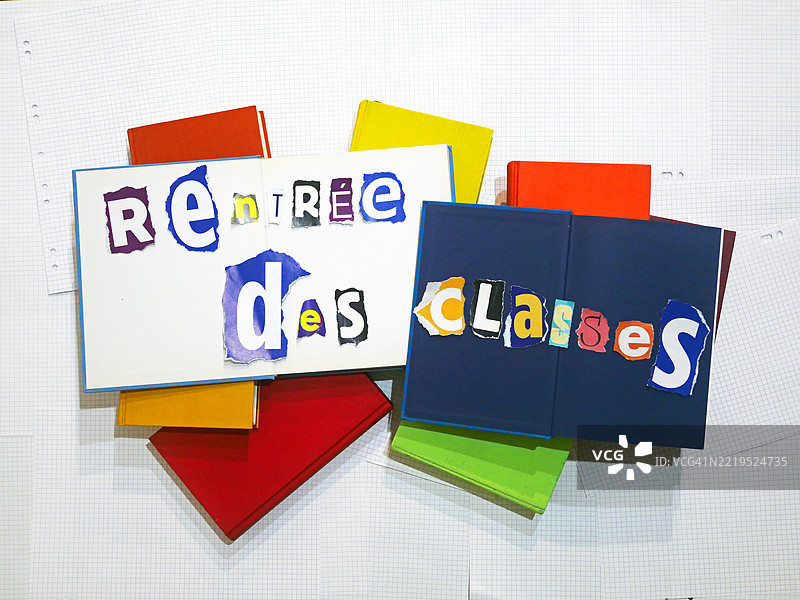 “返校季”用法语写成,字母五彩缤纷且各不相同,剪贴在书本上。背景是带格子的纸张。巴黎,法国。图片素材