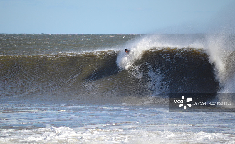 在新泽西州长枝，男子在海中冲浪，背景是天空。图片素材