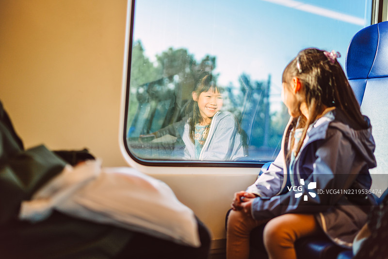 孩子在火车上与家人旅行时，微笑着看着自己的倒影图片素材