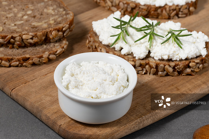 美味的黑麦面包上铺满了奶油奶酪和新鲜香草，放在粗犷的木板上图片素材