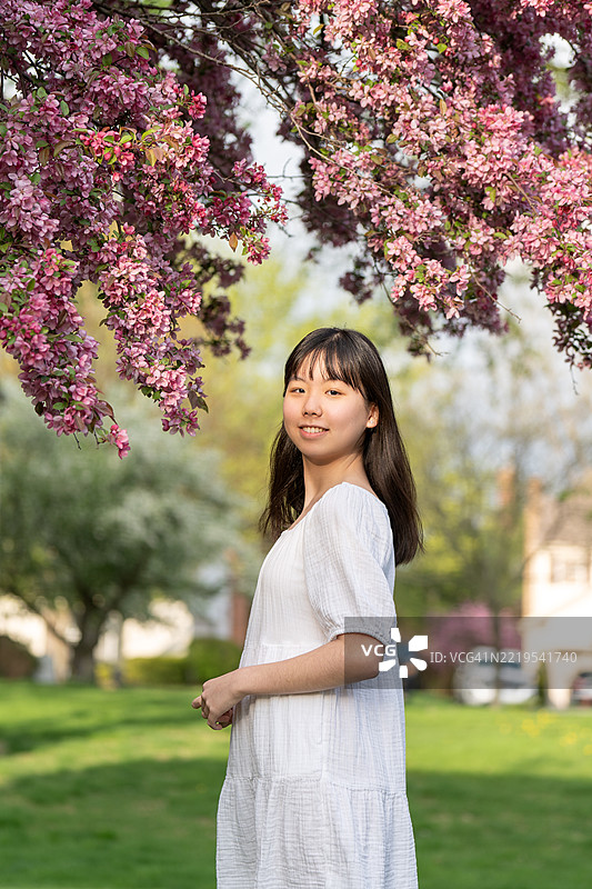 微笑的少女在粉色花树下的肖像图片素材