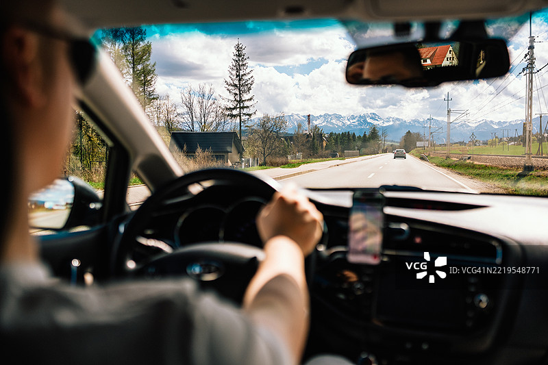 游客在阳光明媚的日子里开车，使用智能手机导航前往高地。图片素材
