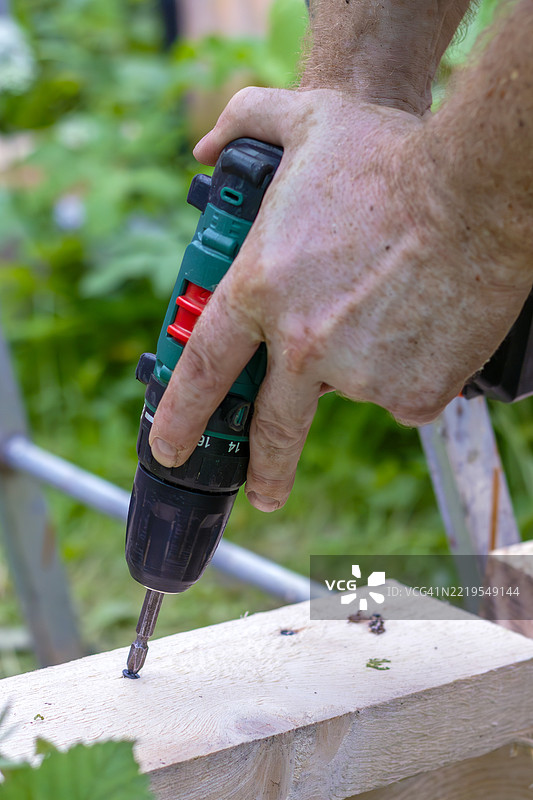 男人的手正在使用电钻组装木结构，DIY需要精准和技巧。图片素材