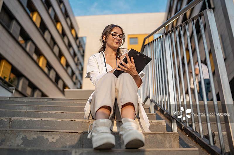 年轻女性坐在现代城市台阶上学习图片素材