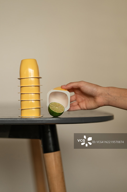 桌子上放着装酸奶、果泥和果冻的塑料杯，旁边有青柠。黄色塑料容器的套装，适合婴儿食品或饮料。食品外卖和外带食品。塑料概念。可重复使用的容器。留白空间。图片素材