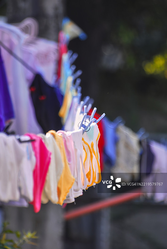 一条晾衣绳上挂着五颜六色的衣物。图片素材