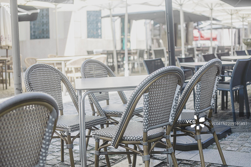 一个村庄酒吧的露台上，所有金属椅子都堆叠着，空无一人。图片素材