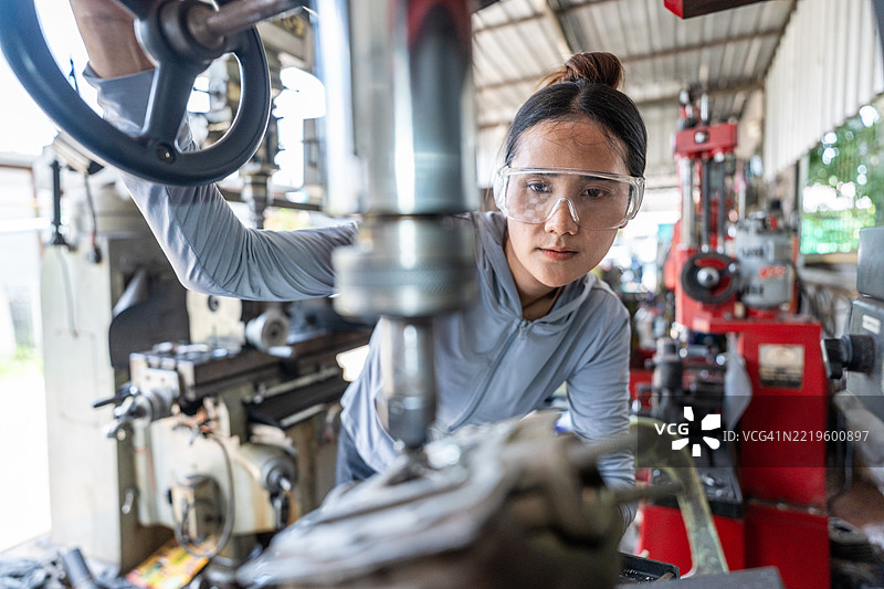 专注的女性机械师在车间使用铣床图片素材