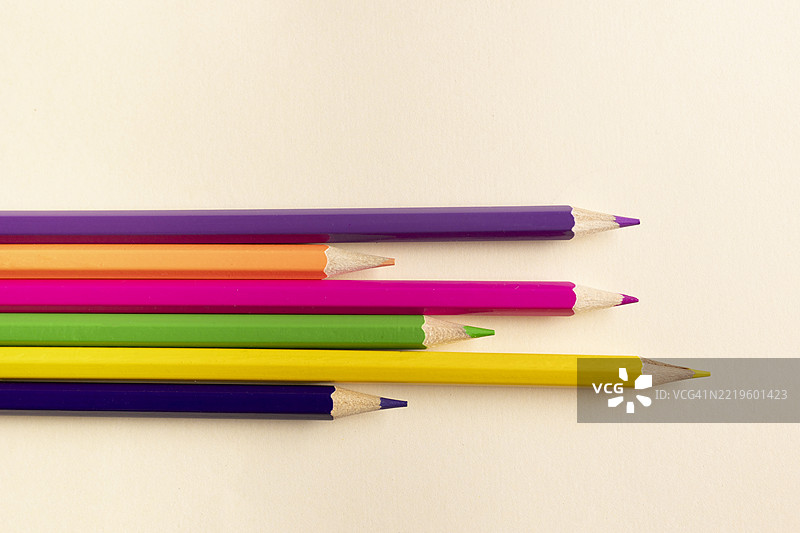五颜六色的铅笔指向不同方向，背景为米色图片素材