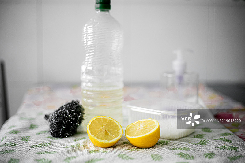 厨房桌子上整齐摆放着天然清洁产品：小苏打、柠檬、醋和一瓶液体肥皂。图片素材