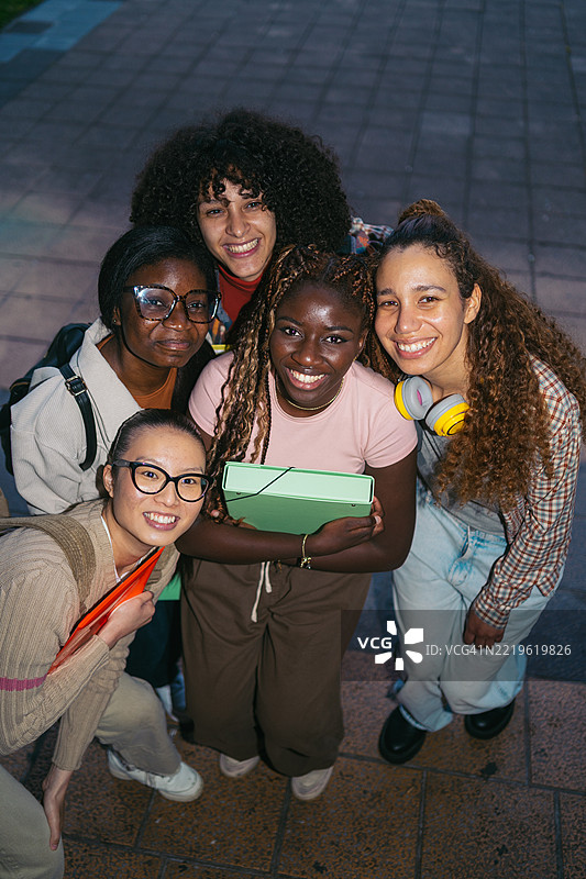 年轻的多民族女性学生们面带笑容，分享毕业的兴奋，真诚地庆祝学业成功。图片素材