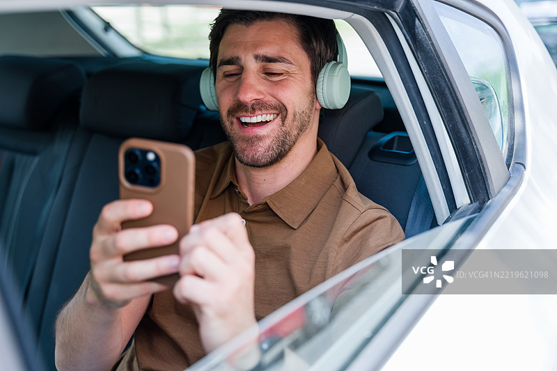 男人在车里享受音乐并使用智能手机图片素材