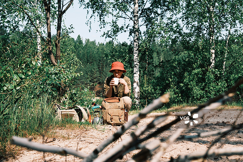 单身女性徒步旅行者在沙滩森林湖岸边喝热茶图片素材