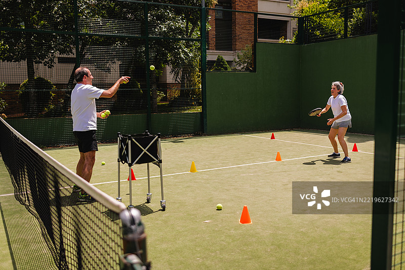 老年夫妇在阳光明媚的壁球场上打壁球图片素材