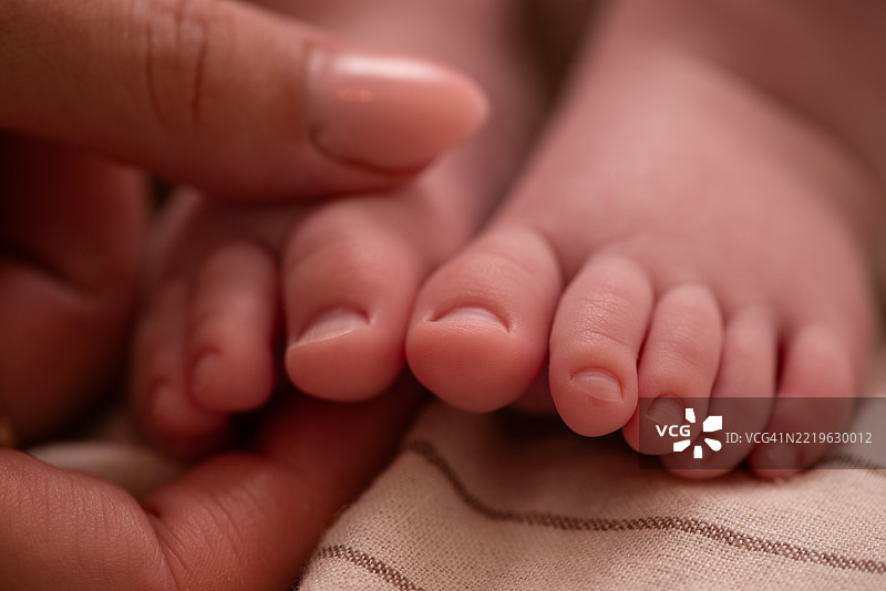 轻柔地触碰婴儿的脚趾。图片素材