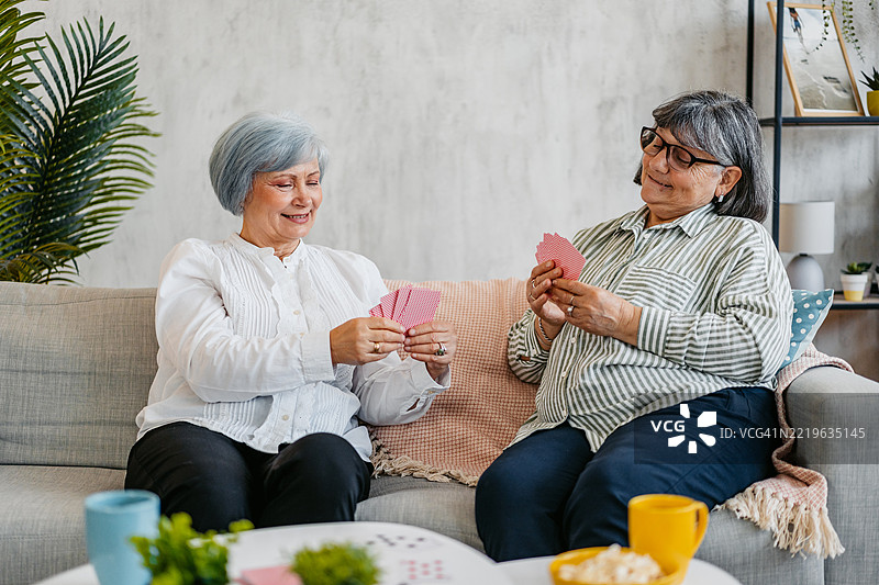 两位年长女性朋友在客厅里一起玩牌图片素材