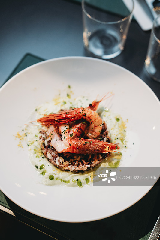 美味的红虾躺在黑米上，配以奶油酱。图片素材